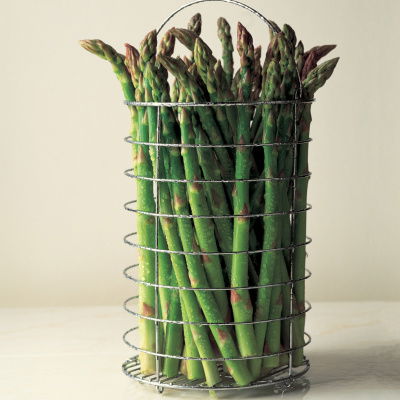 a picture of fresh asparagus in a wire container sitting on a marble surface