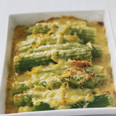 a picture of cooked slices of celery covered in cheese sauce in a white dish