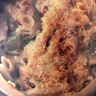 a bowl of penne pasta with leeks and bacon