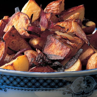 A blue and white patterend china bowl with cooked potatoes and red onion piled up