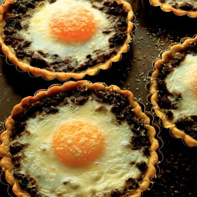 a picture of four individual baked egg tarts on a baking sheet