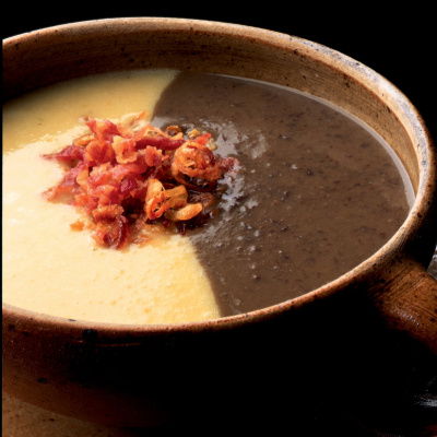 Black and white bean soup in a brown soup dish with crispy bacon crumbled on the top