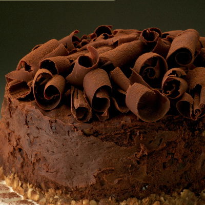 a picture of chocolate cheesecake on a white plate, with chocolate curls on the top